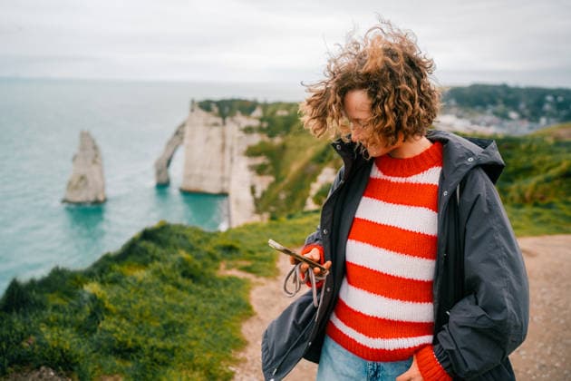 Woman checking a mobile phone on a cloudy day Étretat, Normandy, France CR_UJEL260410-1997950-01 ,model released, Symbolfoto