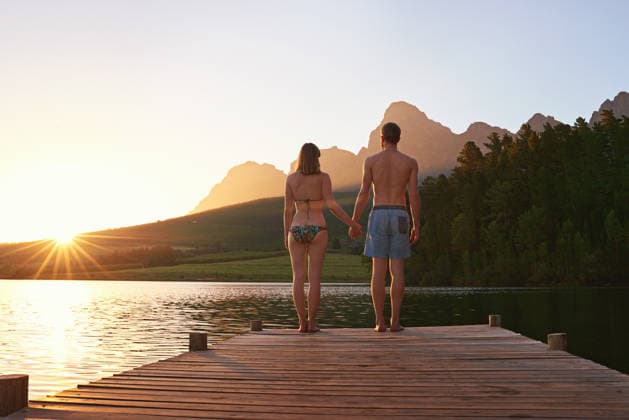 Rearview shot of a young couple in swimsuits standing on a dock at sunset. (License=RF) ,model released, Symbolfoto  Copyright: xZoonar.com KasperxRavlox 18481947 ,model released, Symbolfoto ,property released