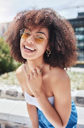 Portrait of young trendy beautiful mixed race woman with an afro smiling and laughing alone outside in the city. Hispanic woman wearing sunglasses and feeling happy. Fashionable African American woman. (License=RF) ,model released, Symbolfoto  Copyright: xZoonar.com YurixArcursxpeopleimages.comx 18805852 ,model released, Symbolfoto ,property released