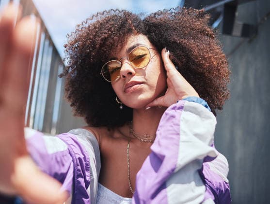 Portrait of young trendy beautiful mixed race woman with an afro taking selfies and posing alone outside. Hispanic woman with curly hair wearing sunglasses. Fashionable African American woman in city. (License=RF) ,model released, Symbolfoto  Copyright: xZoonar.com YurixArcursxpeopleimages.comx 18805891 ,model released, Symbolfoto ,property released