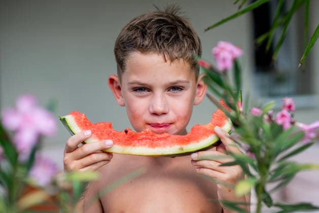 Boy eating watermelon during hot summer day Boy eating watermelon during hot summer day. Looking at camera. model released
