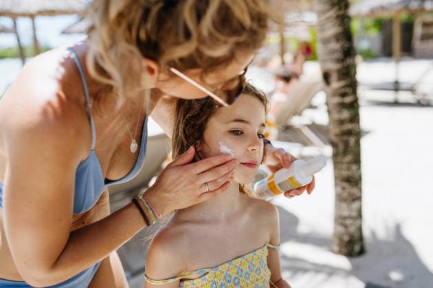 Mother applying sunscreen on daughters face. Mother applying sunscreen on daughter at tropical beach resort. model released