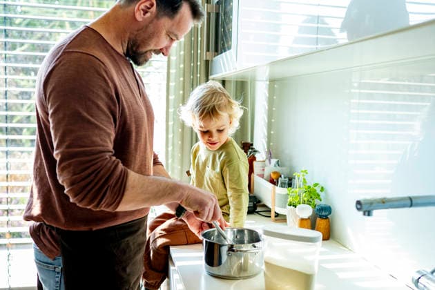 Dad and toddler preparing simple meal together in bright kitchen. Dad and toddler preparing simple meal together in bright kitchen, cooking porridge. model released
