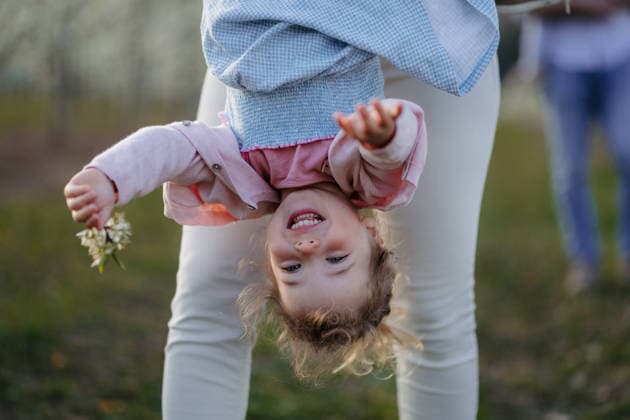 Parent lifting children upside down during playful springtime moment. Parent lifting children upside down during playful springtime moment. Outdoor time. model released