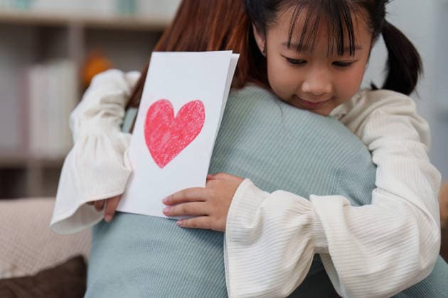 Tochter umarmt ihre Mutter und überreicht ihr eine herzliche Karte zum Muttertag A touching scene of a daughter hugging her mother while holding a card with a red heart, expressing love on Mother s Day. (License=RF) ,model released, Symbolfoto Copyright: xZoonar.com WORAWEExMEEPIANx 24872459 ,model released, Symbolfoto ,property released