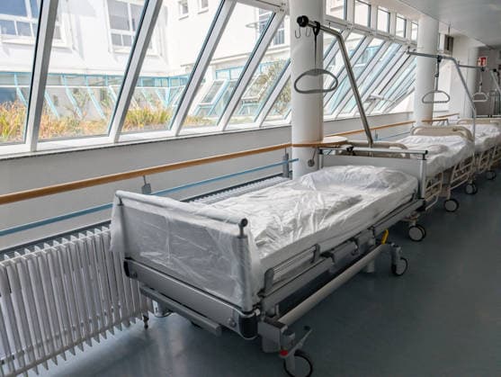 Leere Krankenhausbetten in einer Klinik stehen symbolisch für Pflegenotstand und Kliniksterben. Die Szene verweist auf Herausforderungen im Gesundheitswesen wie Personalmangel, Reformbedarf und die Sicherung der medizinischen Versorgung