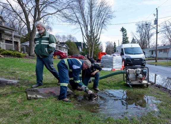 April 22, 2026, Montreal, Pq, CANADA: Homeowner Leslie-Alan Hughes, left watches as city workers pump water from the sewer system back into the flood plain behind his house on Ile Bizard, Que., on Wednesday, April 22, 2026. Montreal CANADA  - ZUMA Apr 20260422_zaf_c35_096 Copyright: xChristinnexMuschix