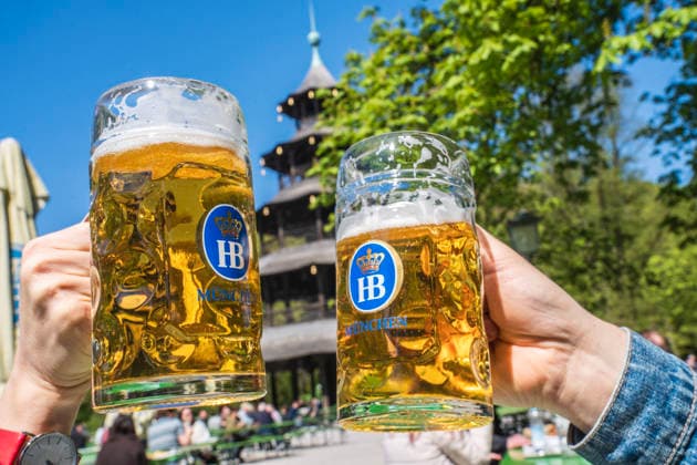 Biergarten am Chinesischen Turm, Frühlingstag im Englischen Garten, zwei Gäste stoßen mit ihrer Mass Bier an, München, April 2026 Deutschland, München, 22. April 2026, Biergarten am Chinesischen Turm, Frühling im Englischen Garten, Temperaturen bis 16 Grad, viele genießen die Sonne bei Bier und einer Brotzeit, zwei Gäste staßen mit ihren Masskrügen an, alles ist grün, Mittwochmittag, Bayern *** Beer garden at the Chinese Tower, spring day in the English Garden, two guests toast with their mugs of beer, Munich, April 2026 Germany, Munich, April 22, 2026, Beer garden at the Chinese Tower, spring in the English Garden, temperatures up to 16 degrees, many enjoy the sun with beer and a snack, two guests toast with their mugs, everythi