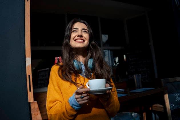 Happy young woman holding coffee cup outside cafe model released, Symbolfoto property released, JOSEF24310