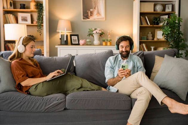 Two people relaxing on a sofa using laptop and mobile phone with headphones model released, Symbolfoto property released, FLMZF01341