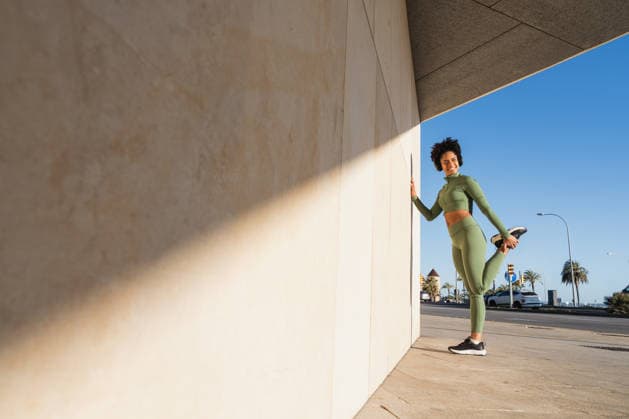 Athlete in green sportswear stretching outdoors against modern wall model released, Symbolfoto, MRF02595
