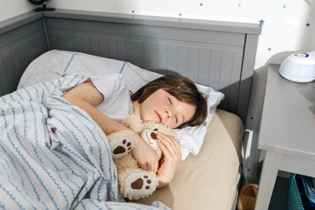 Boy sleeping peacefully in a cozy bed hugging a teddy bear at home model released, Symbolfoto property released, ELMF01276