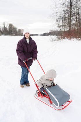 Mother pushing her son in a sled through the snow model released, Symbolfoto, EYAF03999