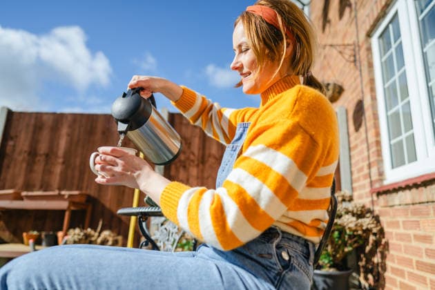 Woman pouring hot tea from thermos in sunny backyard model released, Symbolfoto property released, IGEF00822