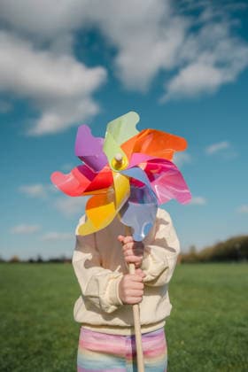 Child holding colorful pinwheel toy at the park on a sunny day model released, Symbolfoto, IGEF00867