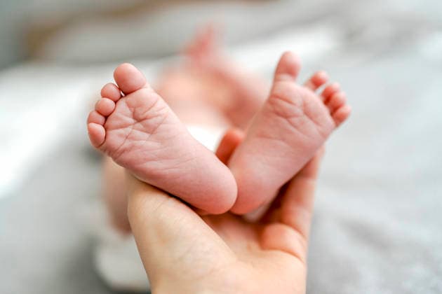 Parent hand holding newborn foot indoors with tenderness model released, Symbolfoto property released, NSTF00618