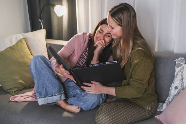 Mother and daughter looking at photo album together on sofa model released, Symbolfoto, TSF00783