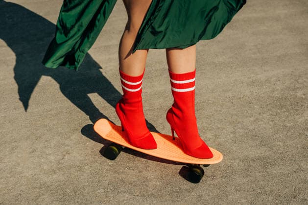 Legs in red high heel balancing on an orange skateboard model released, Symbolfoto, VSNF04744