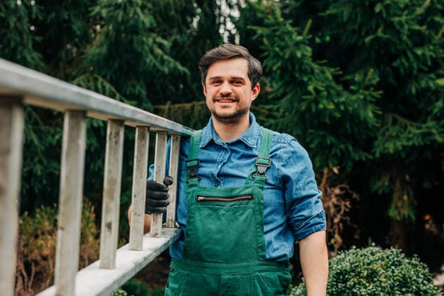 Smiling gardener carrying ladder outdoors for spring tree care model released, Symbolfoto, VSNF04768