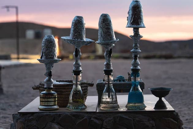 Shisha hookahs with foil-topped bowls on a stone table in marsa alam desert at sunset, traditional water pipes creating a tranquil, warm evening atmosphere for relaxation Shisha hookahs on desert table at sunset in marsa alam Copyright: xFilippoxCarlotx Egitto comm 390