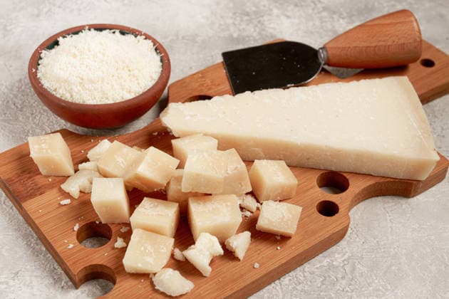 Frisch geschnittener und geriebener Käse, Parmesan, auf einem hölzernen Schneidebrett, auf rustikale Art, ohne Menschen Freshly sliced and grated cheese, parmesan cheese, Gran gusto. Grana padano. on a wooden chopping board, rustic style, no people (License=RF) Copyright: xZoonar.com GalinaxDidebashvilix 24938236