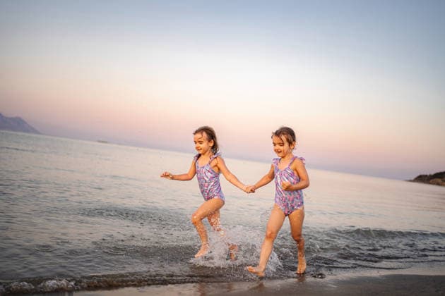Glückliche Zwillingsschwestern, die Händchen haltend im griechischen Meer planschen Young twin sisters running on the beach, splashing in the sea during a summer vacation (License=RF) ,model released, Symbolfoto Copyright: xZoonar.com JelenaxCvetkovicx 24949554 ,model released, Symbolfoto ,property released