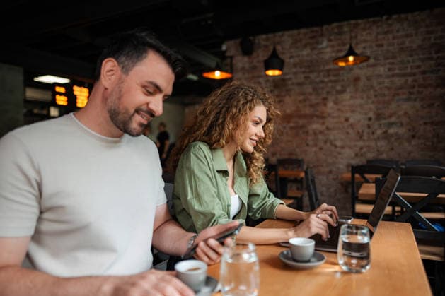 Ein junges Paar, das in einem Café an seinen Geräten arbeitet und Kaffee trinkt Young smiling couple using laptop and smartphone while drinking coffee in a cafe (License=RF) ,model released, Symbolfoto Copyright: xZoonar.com JelenaxCvetkovicx 24957096 ,model released, Symbolfoto ,property released