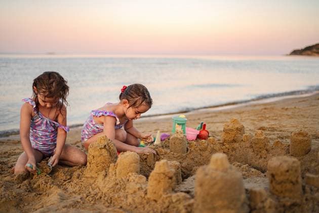 Sandburg-Abenteuer bei Sonnenuntergang mit der Familie am Meeresufer Two young siblings joyfully building sandcastles on a serene beach at dusk. (License=RF) ,model released, Symbolfoto Copyright: xZoonar.com JelenaxCvetkovicx 24958400 ,model released, Symbolfoto ,property released