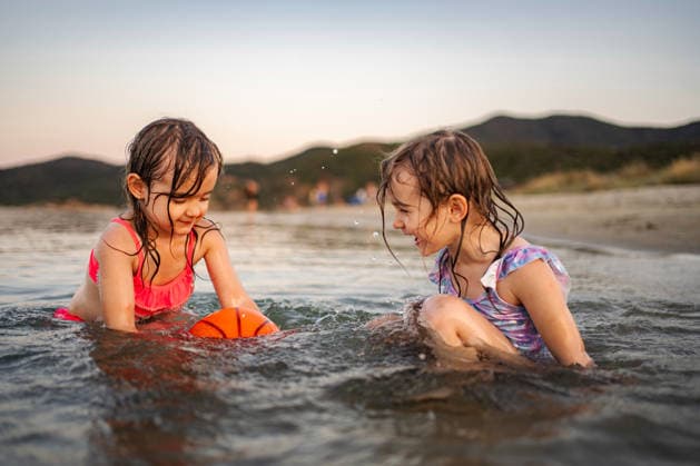 Fröhliche kleine Mädchen, die ihre Sommerferien genießen und im Wasser spielen Two young sisters having fun splashing water on ocean beach at sunset (License=RF) ,model released, Symbolfoto Copyright: xZoonar.com JelenaxCvetkovicx 24959121 ,model released, Symbolfoto ,property released