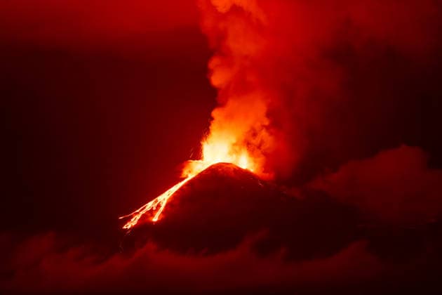 Creative Highlights World Vulkanausbruch mit Lavastrom und rotem Rauch Etna erupts at night with lava flowing down the slope, red smoke clouds rise into the sky above the summit, surrounded by dark mist. (License=RF) Copyright: xZoonar.com DetlefxVoigtxinfo@gph-foto.dex 24962158