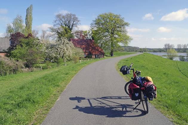 Ein bepacktes Fahrrad auf einem ländlichen Weg entlang eines Flusses, Fahrrastourismus, Deich, Elberadweg, elbe, Damnatz, Wendland, Niedersachsen, Deutschland A packed bike on a rural path along a river, bicycle tourism, dyke, Elbe cycle path, Elbe, Damnatz, Wendland, Lower Saxony, Germany Copyright: imageBROKER ReinhardxPantke iblrpa17480760.jpg