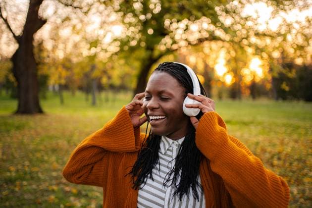 Eine fröhliche junge Frau, die im Herbst im Park Musik im Freien genießt Young black woman smiling, listening to music with headphones in an autumn park (License=RF) ,model released, Symbolfoto Copyright: xZoonar.com JelenaxCvetkovicx 24971453 ,model released, Symbolfoto ,property released