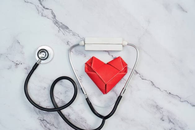 Stethoskop und rotes Origami-Herz auf weißem Marmorhintergrund, Kardiologie A classic medical stethoscope is paired with a symbolic red origami heart, representing heart health and cardiology. The objects are arranged on a clean white marble surface, conveying a sense of care and precision. (License=RF) Copyright: xZoonar.com WORAWEExMEEPIANx 24988054