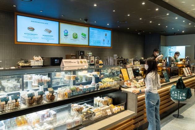 Starbucks schließt in Südkorea temporär alle Filialen, Archivbilder Seoul, South Korea April 28, 2026: A customer places an order at the counter of a Starbucks location, while baked goods and snacks are displayed behind the glass display case and baristas prepare drinks *** Kundin bestellt an der Theke einer Starbucks-Filiale, während hinter der Glasvitrine Backwaren und Snacks ausgestellt sind und Baristas Getränke zubereiten