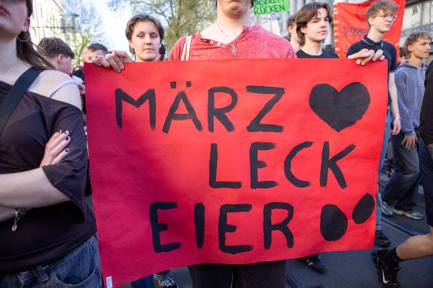 News Bilder des Tages May 1, 2026, Leipzig, Saxony, Germany: A protester holds a banner that reads in German Ã¢â‚¬oeMoÂ¤rz, lick eggs.Ã¢â‚¬Â? referring to the German chancellor Merz during the protests of 1 Mai in Leipzig. Leipzig Germany  - ZUMAc291 20260501_zip_c291_017 Copyright: xMariaxCastrox