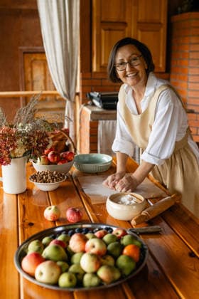 Smiling baker in apron kneading dough on veranda with fresh apples model released, Symbolfoto property released, MKVF00208