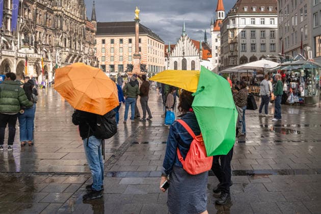 Nach Wolkenbruch und Gewitter blinzelt schon wieder die Sonne durch eine Wolkenlücke und taucht den Marienplatz in ein wunderbares Licht, Passanten mit bunten Regenschirmen, München, 6. Mai 2026 Deutschland, München, 6. Mai 2026, nach Wolkenbruch scheint schon wieder die Sonne über dem Marienplatz, Passanten mit bunten Regenschirmen, zuvor heftiger Starkregen mit Gewitter, Mitwocnachmittag um 17:30 Uhr, Innenstadt, Wirtschaft, Wetter, Unwetter, Frühling, Bayern *** After a cloudburst and thunderstorm, the sun blinks through a gap in the clouds and bathes Marienplatz in a wonderful light, passers-by with colorful umbrellas, Munich, 6 May 2026 Germany, Munich, 6 May 2026, after a cloudburst the sun shines again over Marienplatz, passers-