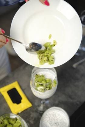 Die Person gibt Kiwi Stücke in das Dessertglas auf dem Tisch, wobei einige Zutaten an einem sonnigen Tag in der Nähe sind Person adds kiwi pieces to dessert glass on table with some ingredients nearby during a sunny day Copyright: imageBROKER AlekseixIsachenko ibxaii17581688.jpg ,model released, Symbolfoto ,property released