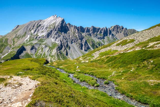 Creative Highlights World Das Alpental und die Felsgipfel der Aiguilles de la Pennaz bei Contamines-Montjoie, Frankreich Green alpine valley with a narrow stream and Aiguilles de la Pennaz towering rocky peaks in bright sunlight near Contamines Montjoie in the French Alps (License=RF) Copyright: xZoonar.com LaurentxDavoustx 25009615