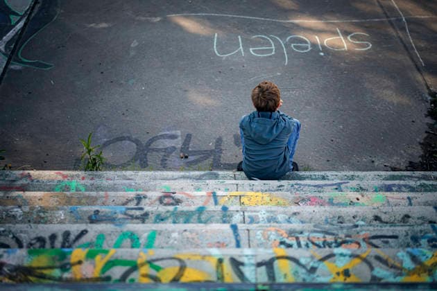 Gestellte Szene. Symbolfoto zum Thema Einsamkeit und Armut bei Kindern. Ein Junge sitzt alleine auf einem mit Graffiti bespruehten, heruntergekommenen Spielplatz. Glienicke, 08.05.2026. Glienicke Deutschland *** Staged scene Symbolic photo on the subject of loneliness and poverty among children A boy sits alone on a run-down playground covered in graffiti Glienicke, 08 05 2026 Glienicke Germany Copyright: xThomasxTrutschelx