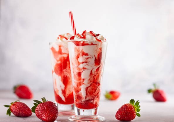 Erdbeermilchshake mit Schlagsahne. Strawberry milkshake with whipped cream and berry syrup in the tall glass on light background. (License=RF) Copyright: xZoonar.com SvetlanaxKolpakovax 25044113