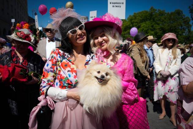 (260511) -- WARSAW, May 11, 2026 -- Women holding a pet dog pose for photos during the Hat Walk Warsaw event in Warsaw, Poland, May 10, 2026. Participants of the Hat Walk Warsaw event walked along main streets in the city s Old Town to showcase creativity and personal style. (Photo by Xinhua) POLAND-WARSAW-HAT WALK JaapxArriens 