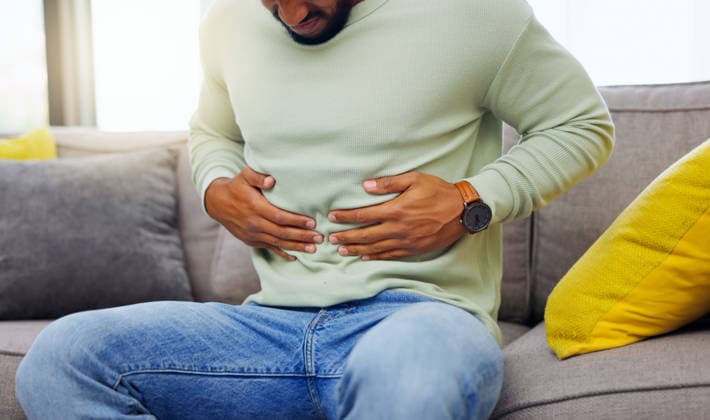 Man on a sofa with stomach pain, sickness or cramps while relaxing in the living room at his home. Medical emergency, illness and male with diarrhea, indigestion or food poisoning ache at his house (License=RF) ,model released, Symbolfoto  Copyright: xZoonar.com YurixArcursxpeopleimages.comx 20609042 ,model released, Symbolfoto ,property released