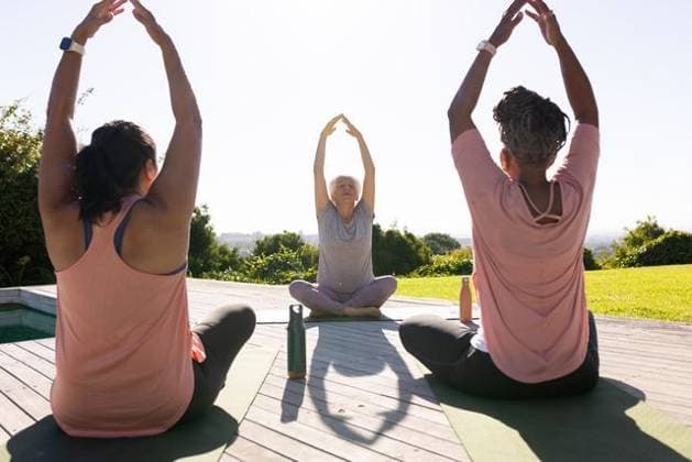 Senior woman with two women stretching on yoga mats by pool on wooden deck with bottles, model released, property released, Cape Town, South Africa, 20.02.2026 06:00:00, 12423539 Copyright: xIS-260402xcreatorid:x393x 12423539