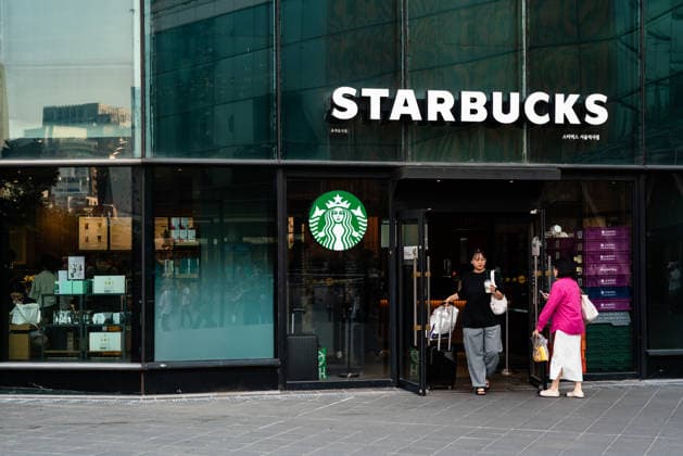 Starbucks schließt in Südkorea temporär alle Filialen, Archivbilder Starbucks in Seoul, South Korea - 15 May 2026 A woman holding a take out coffee walks out of Starbucks in Seoul. Seoul South Korea Copyright: xSimonxShinx xSOPAxImagesx _DSC1187