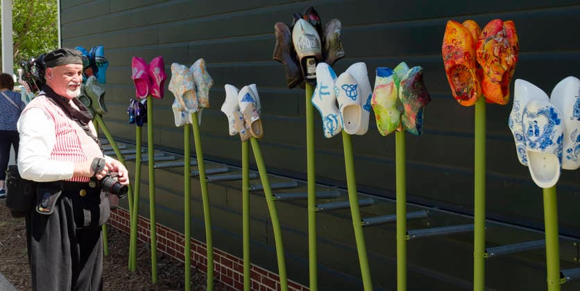 May 15, 2026, Orange City, Iowa, USA: A Photographer dressed in a Dutch costume takes photographs of an art display of painted wooden shoes arranged to look like tulips at the 85th annual Orange City, Iowa 3-day Tulip festival in downtown Orange City, Iowa Friday, May 15, 2026. Orange City USA  - ZUMAm41_ 20260515_zaf_m41_016 Copyright: xJerryxMennengax