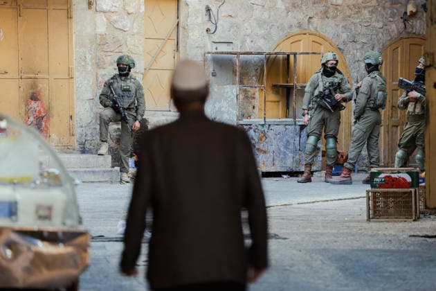 Hebron Israeli Settlers Tour May 16 A man walks in the direction of armed Israeli soldiers standing guard in the Old City of Hebron, the occupied West Bank, on May 16, 2026. The area is routinely secured by troops to allow Israeli settlers to tour the city. Hebron West Bank Palestinian Territories Copyright: xMosabxShawerx