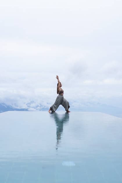 Woman in warrior yoga pose at infinity pool above clouds, Bali Buleleng, Bali, Indonesia CR_YUKI260516D-2021936-01 ,model released, Symbolfoto