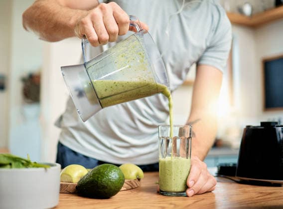 Hands, man and pour green smoothie in home for breakfast shake, health benefits and nutrition. Fruit, person and glass with nutrient beverage in blender for detox drink, healthy diet and weight loss. model released property released Copyright: xwww.peopleimages.comx