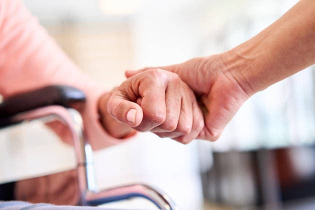 Senior Patient Hand Being Held By Physiotherapist In Rehab Center For Support And Care During Recovery Wheelchair In Background Indoors (License=RF) ,model released, Symbolfoto  Copyright: xZoonar.com RobertxKneschkex 25045438 ,model released, Symbolfoto ,property released